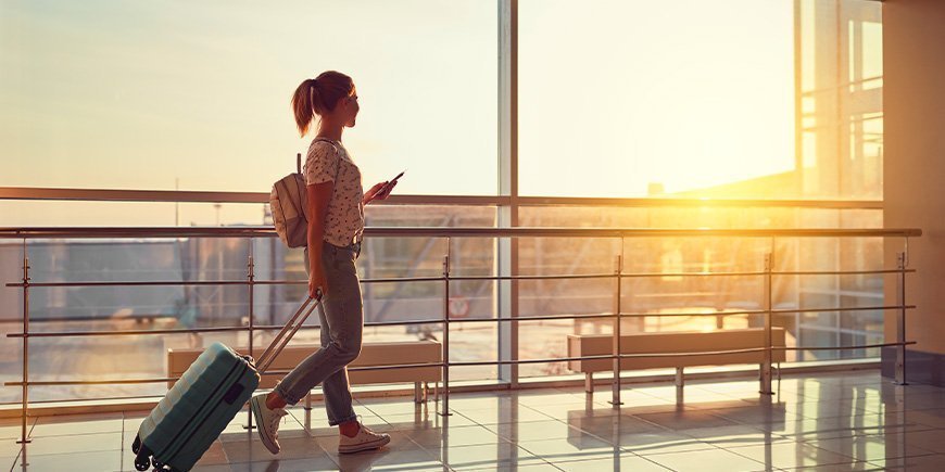 Woman walks through the airport with passport and boarding pass in hand