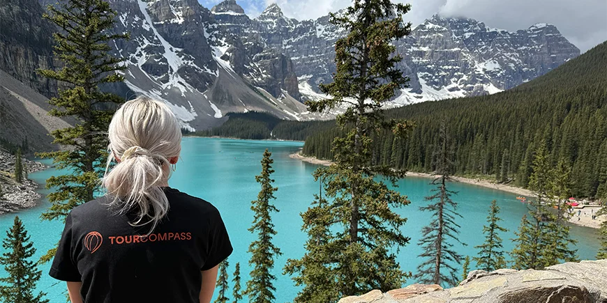 Woman in TourCompass T-shirt looking out over the water at Lake Louise in Canada