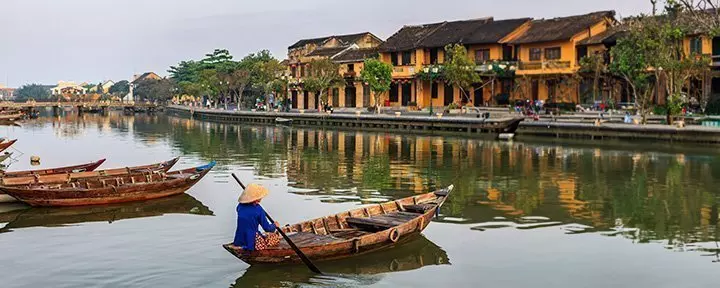 Vietnamese woman paddling in the old district of Hoi An, Vietnam.