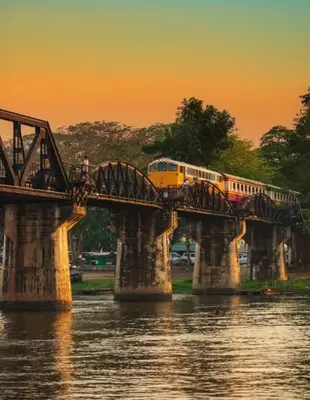 Train on the bridge over the River Kwai at sunset.