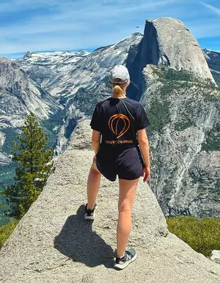 Woman in TourCompass t-shirt on cliff in Yosemite