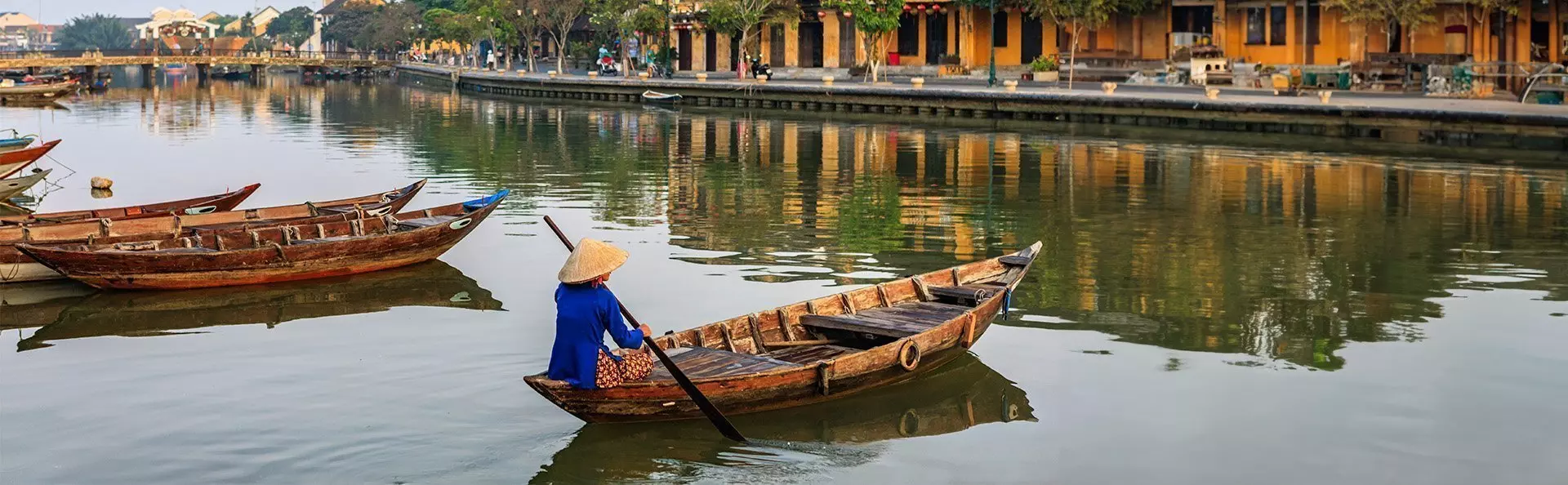 Vietnamese woman paddling in the old district of Hoi An, Vietnam.