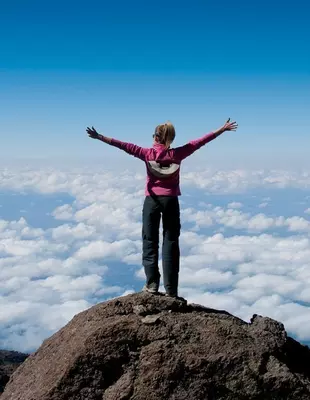 Female trekker standing on a peak on Kilimanjaro