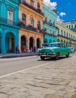 Cityscape with green American vintage car on the main street of Havana City Cuba