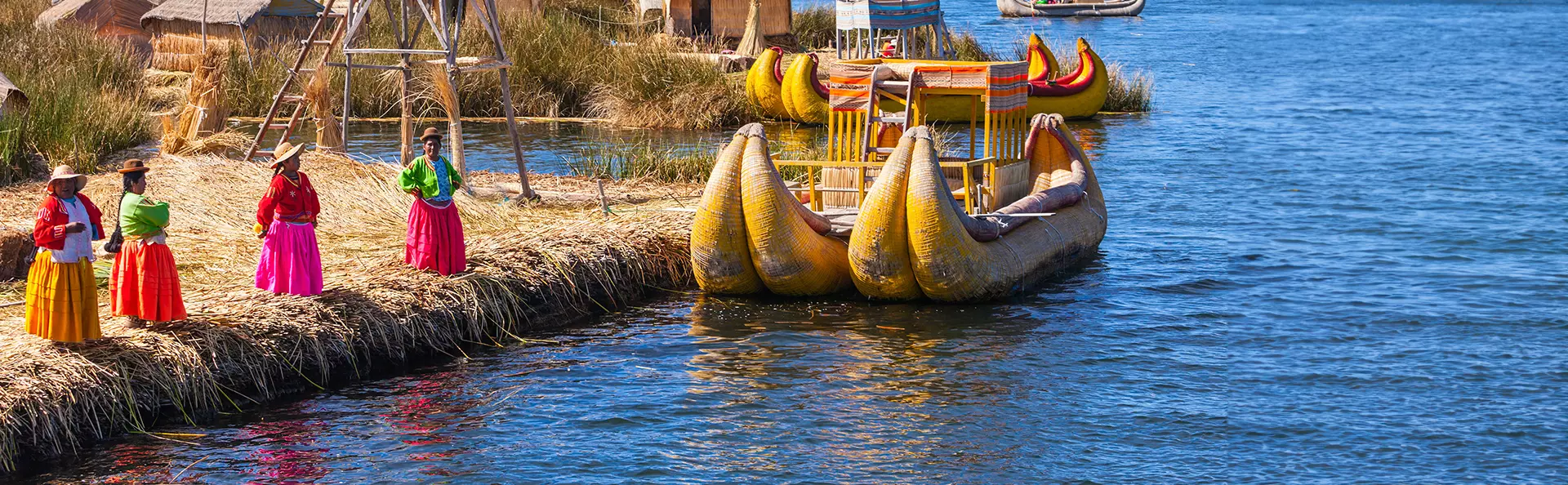 Peruvian women in traditional dress welcoming tourists to Uros Island