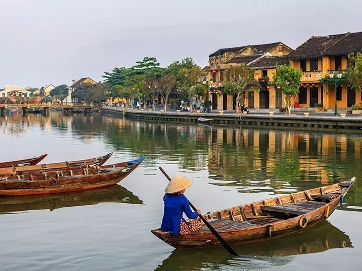 Vietnamese woman paddling in the old district of Hoi An, Vietnam.