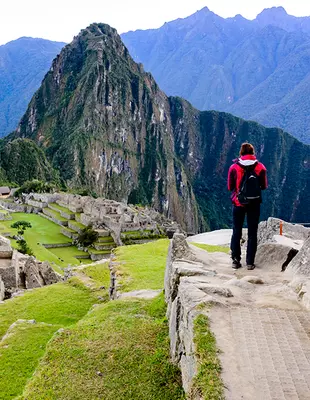 Tourist at the Machu Picchu Inca ruins at sunrise